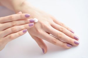 Hyaluronic acid benefits, Women's hands with pink manicure applying cream. The concept of