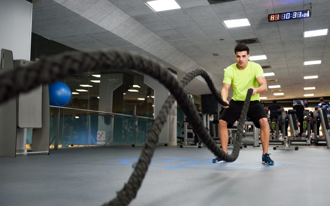 Man with battle ropes exercise in the fitness gym.