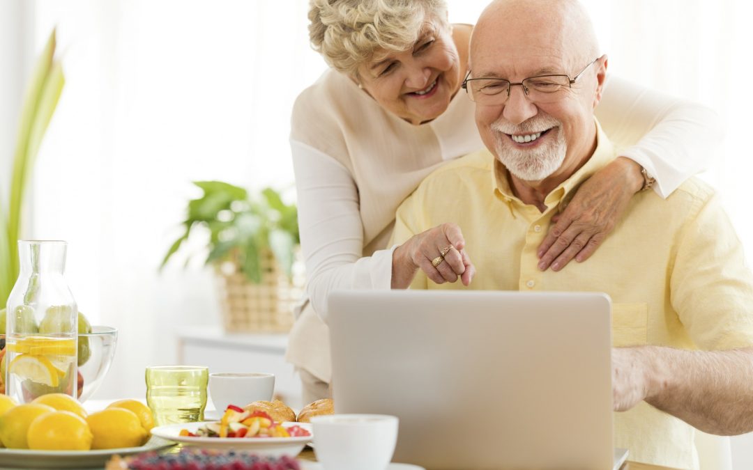 Smiling senior man using laptop with his happy wife. Elderly peo